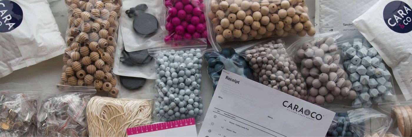 view from above - bags of silicone beads, wood beads, and other crafting products, plus a packing slip from Cara & Co